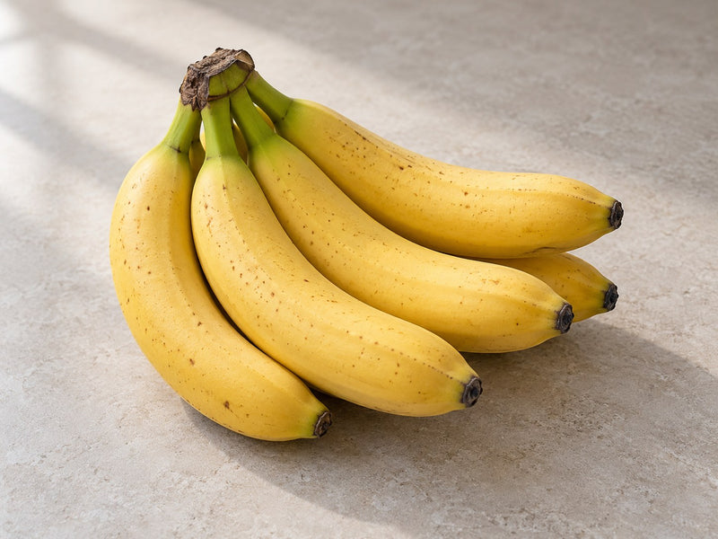 Ein kleines Bündel gelber Bananen auf einer hellen Oberfläche.
