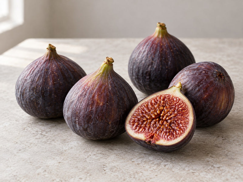 Frische violette Feigen, eine davon aufgeschnitten.