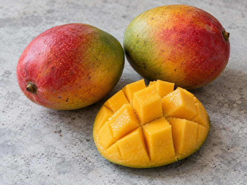 Zwei ganze Mangos und eine aufgeschnittene Mango mit gelbem Fruchtfleisch.