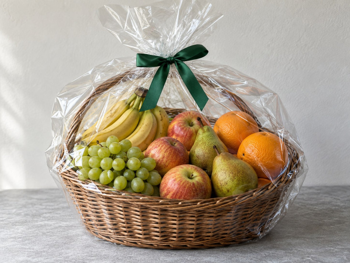 Geschenkkorb mit frischem Obst, transparenter Verpackung und grünem Band.