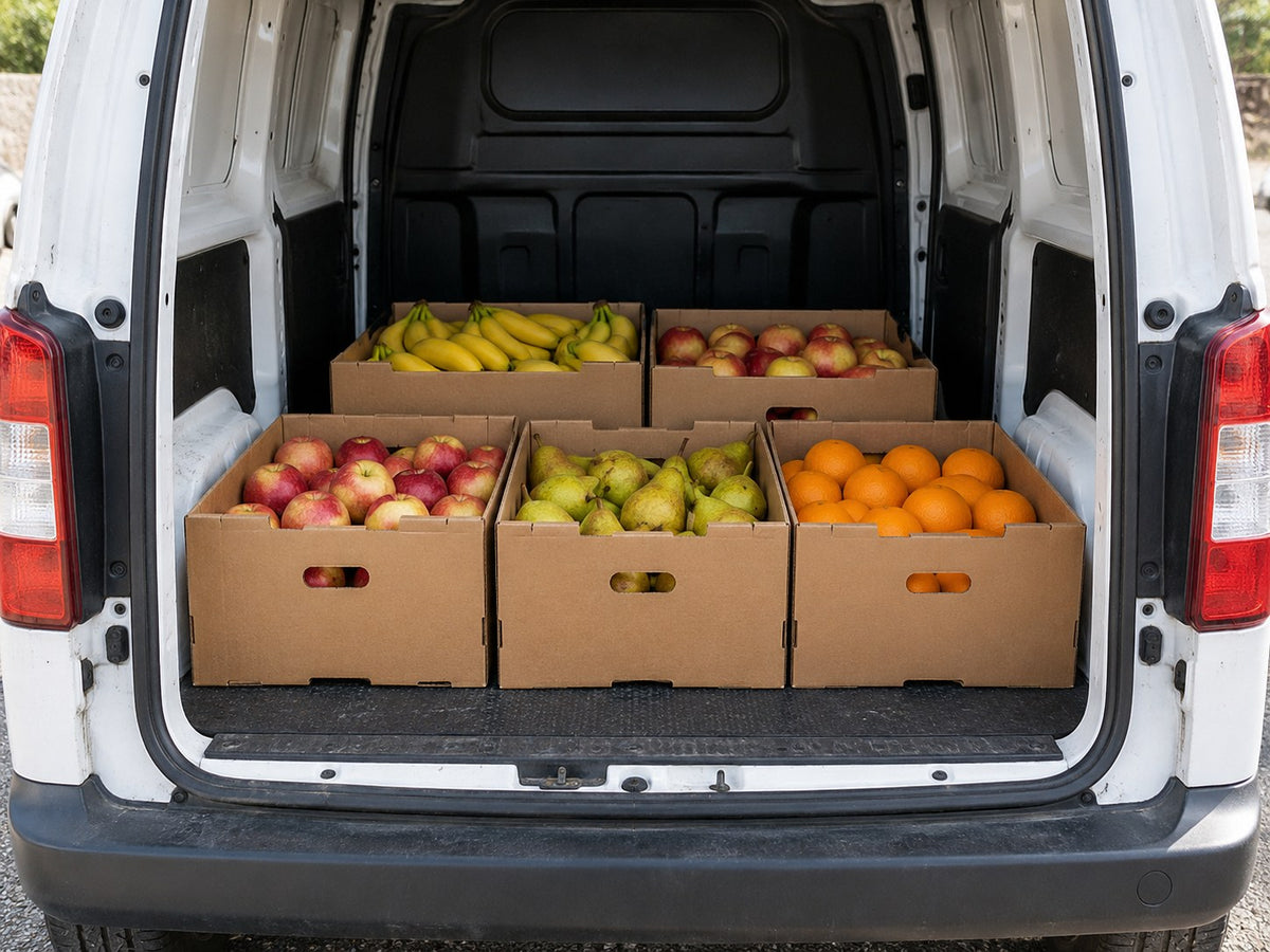 Gefüllte Obstkartons im geöffneten Laderaum eines weißen Lieferwagens.