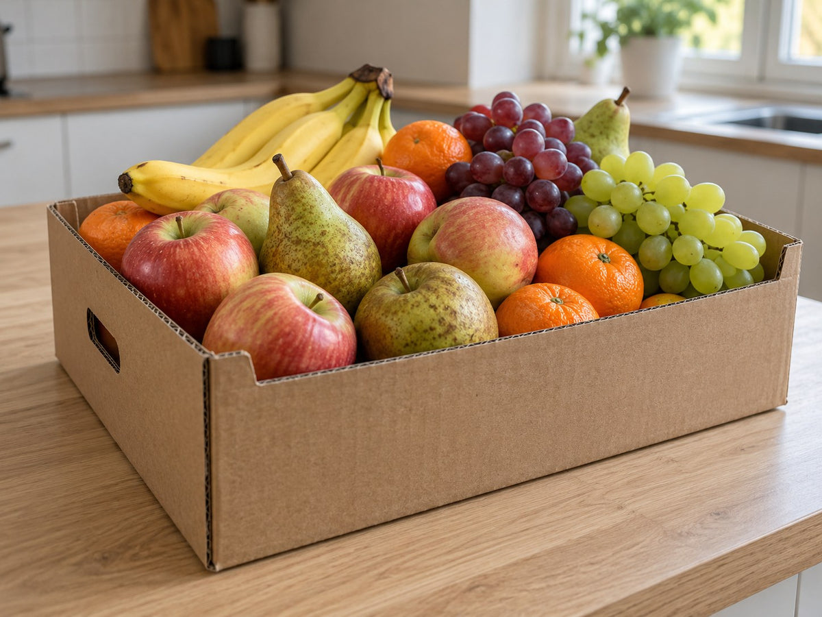 Gefüllte Obstkiste auf einer hellen Kücheninsel am Fenster.