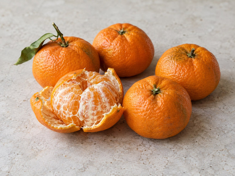 Fünf Satsuma-Mandarinen, eine davon teilweise geschält.