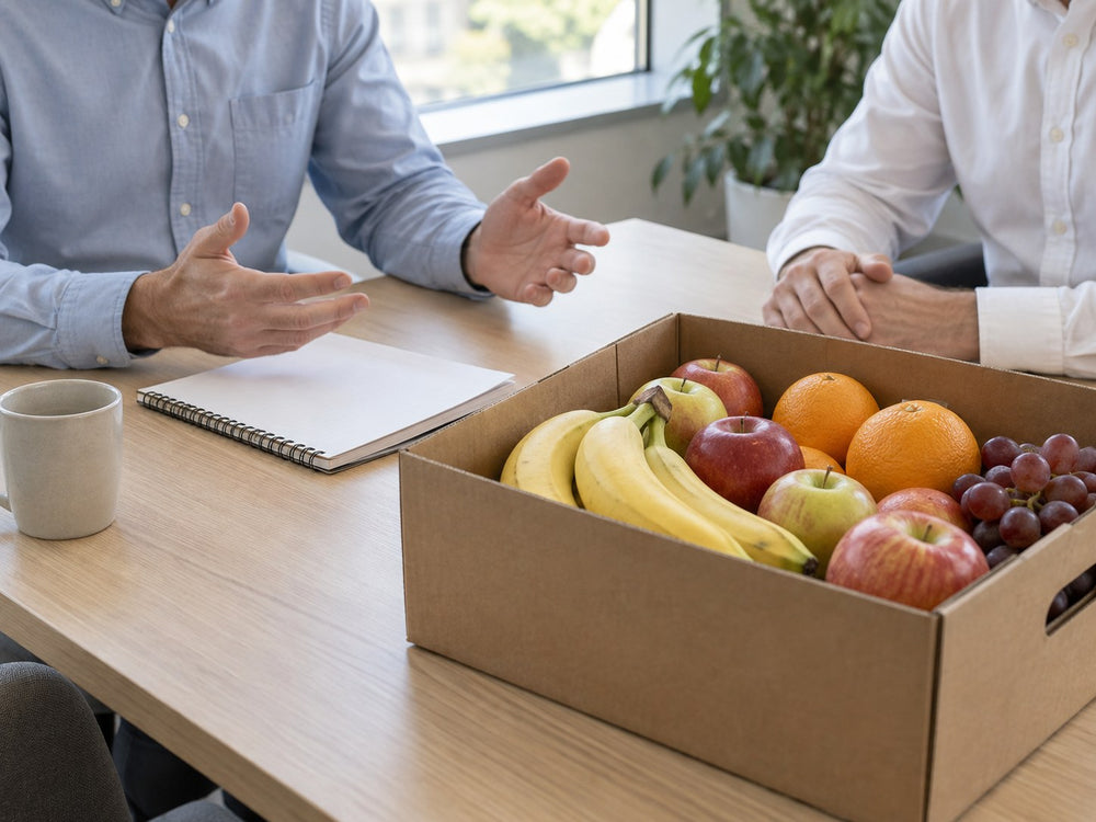 Zwei Erwachsene besprechen eine Obstlieferung neben einer gefüllten Kiste im Büro.